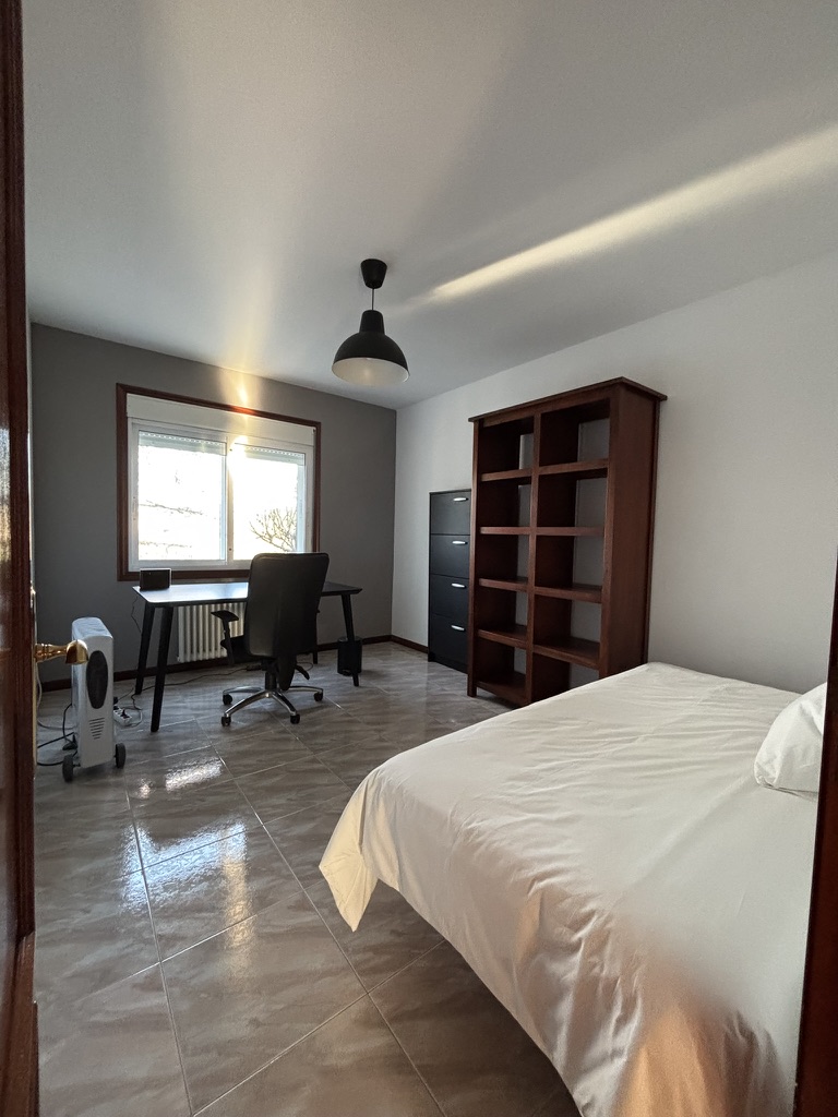 Dormitorio estudio con escritorio de trabajo, estantería de madera y decoración minimalista